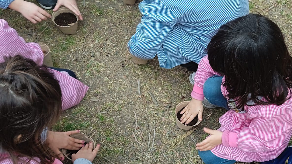 Bambini riempiono i vasetti di terra