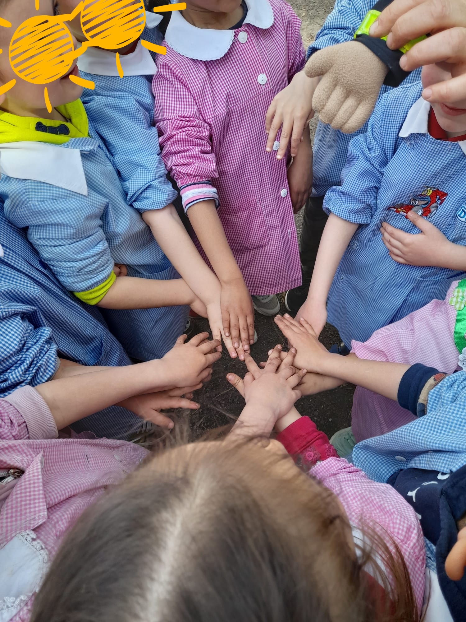 Bambini in cerchio che congiungono le mani al centro